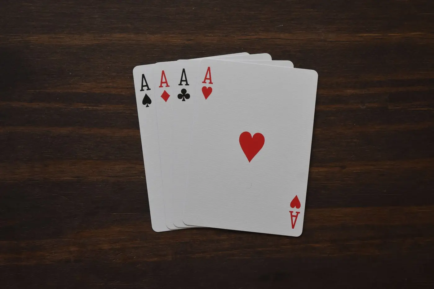 Four aces of different suits on a wooden table